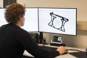Man werkt aan 3D-modelontwerp op computerschermen.